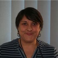 A woman wearing a striped shirt stands in front of a window, representing her position as Chair of the Local Governing Body.